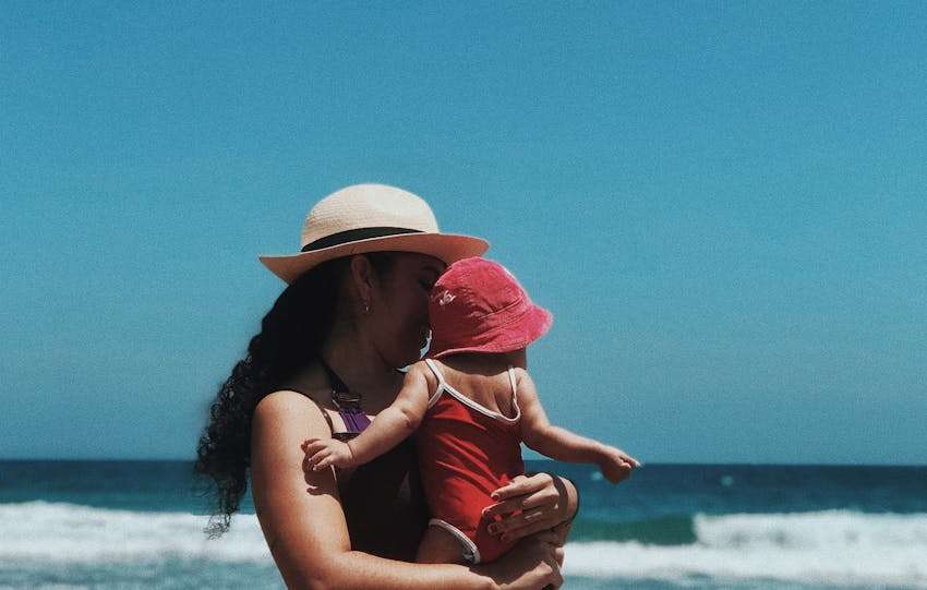 vrouw tilt een baby op het strand