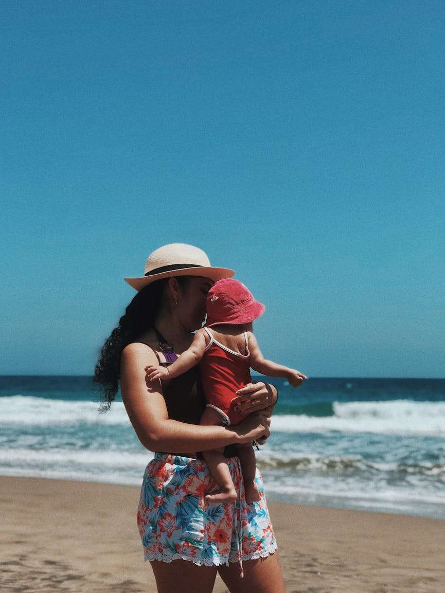 vrouw tilt een baby op het strand